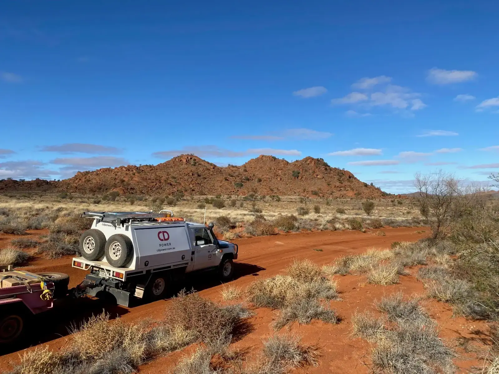CD Power service vehicle parked on a red dirt road in the outback with rocky hills behind it