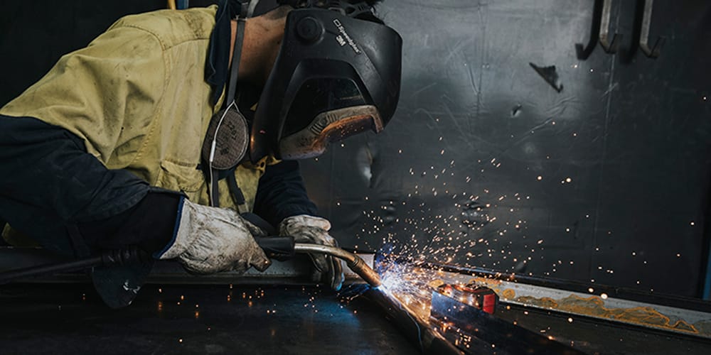 Welder fabricating a metal piece with bright sparks in a workshop