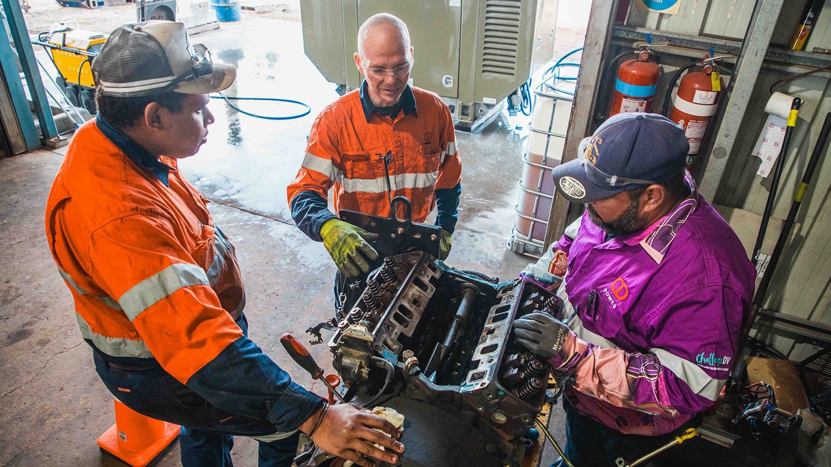 Three CD Power technicians repairing a generator engine in a workshop