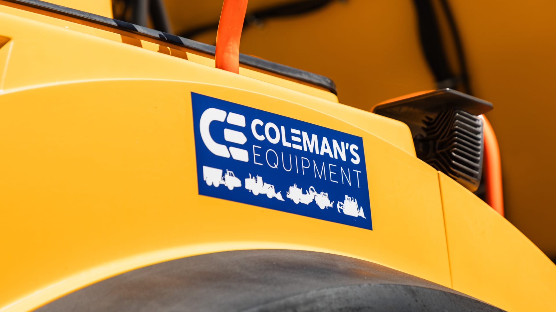 Blue Coleman's Equipment sticker applied to the yellow bodywork of a machine