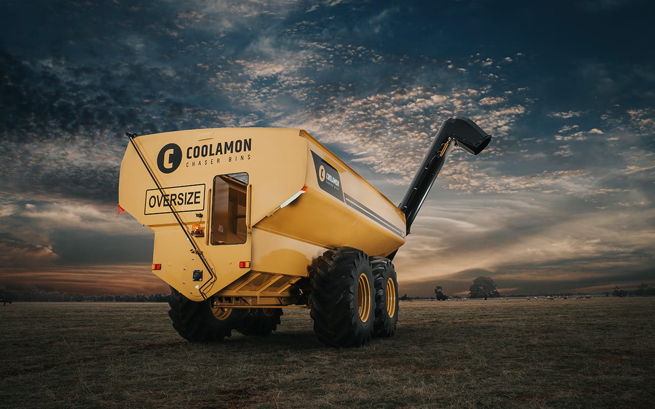 Yellow Coolamon chaser bin parked in an open field under a sunset sky
