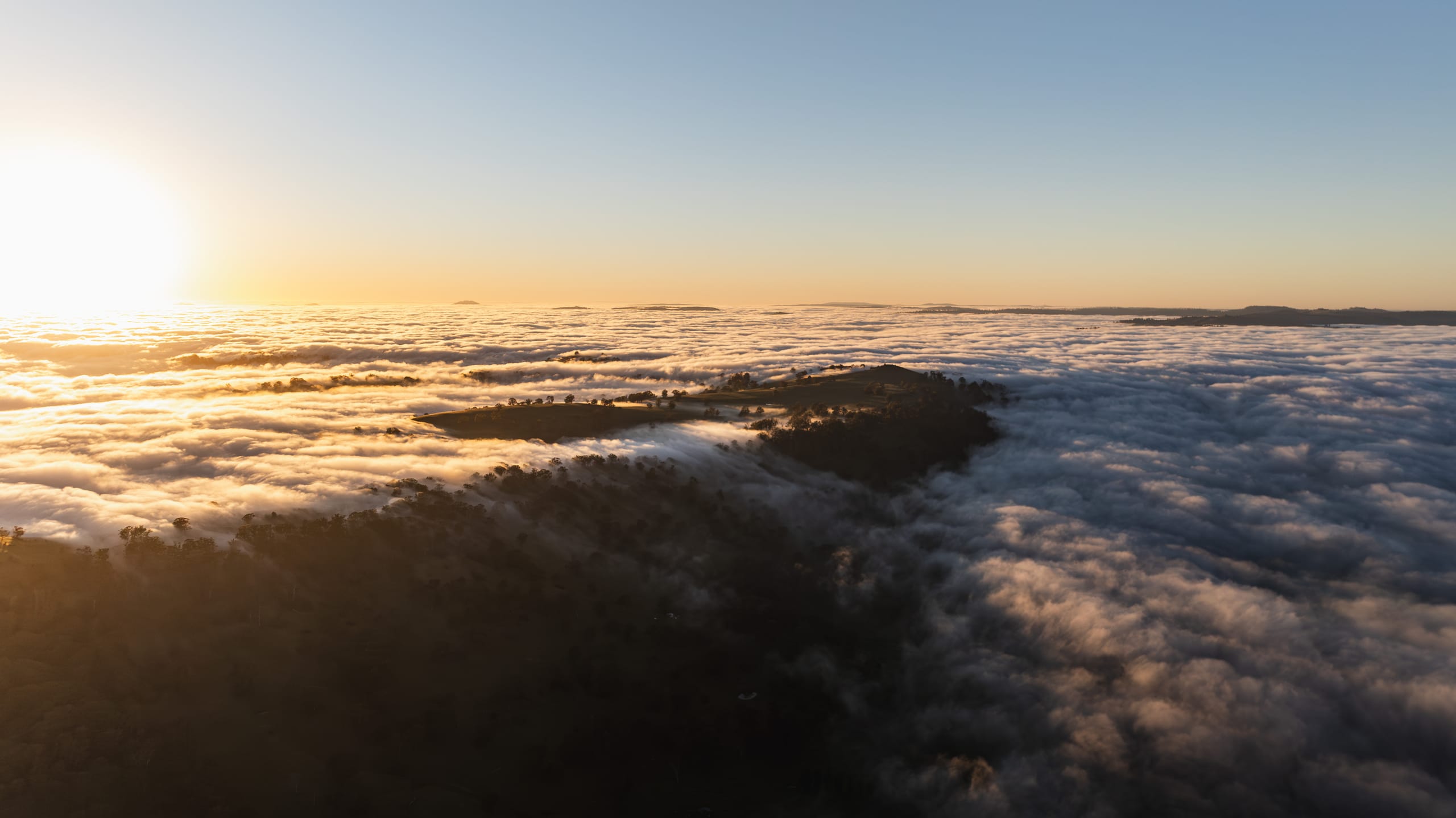 Sunrise breaking over low cloud and rolling farmland