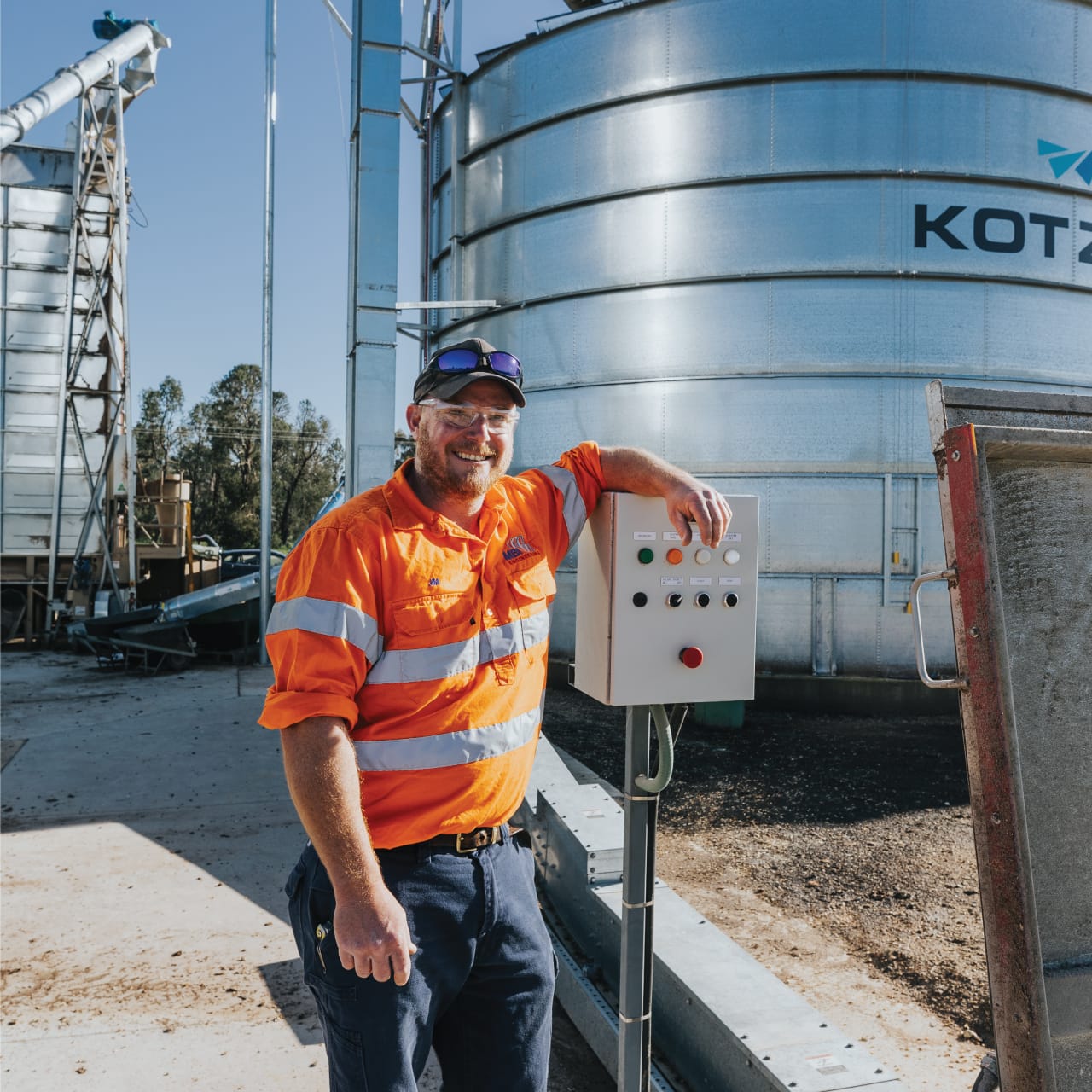 MBI Engineering worker standing beside a control panel at a grain silo site