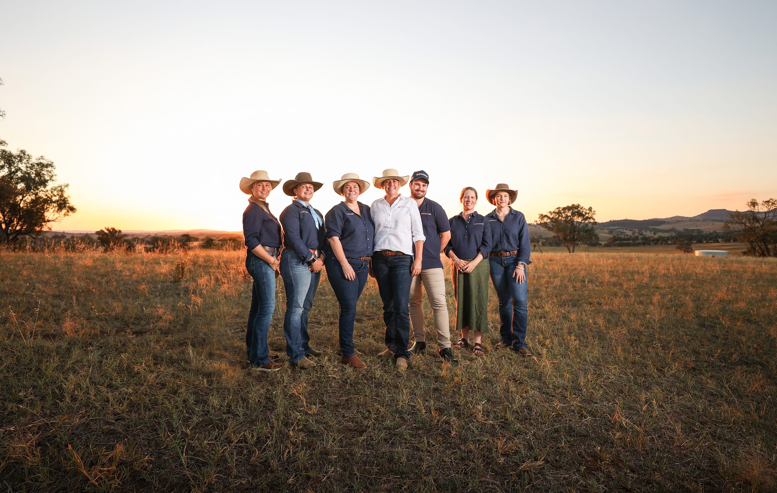 Wide portrait of the StockLive team standing in a paddock at golden hour