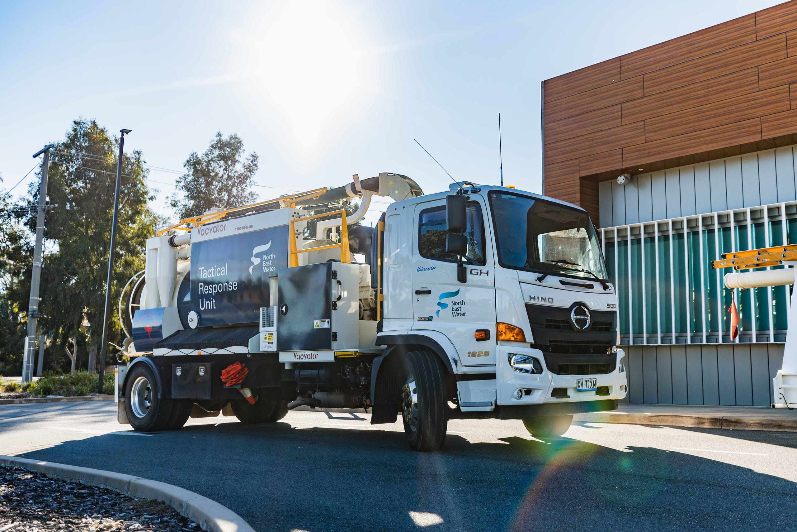 Vacvator vacuum truck parked outside an industrial building in bright sunlight